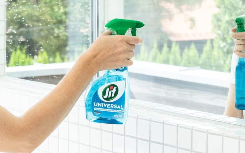 Kvinne vasker speil med Jif Universal.