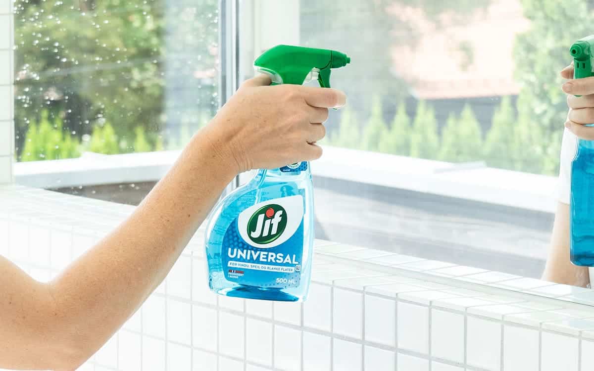 Kvinne vasker speil med Jif Universal.