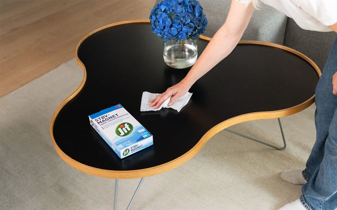 Kvinne fjerner støv fra bord med Jif Støvmagnet.